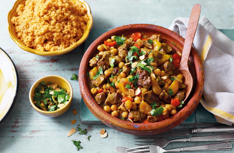 Bàn ăn Maroc truyền thống với tagine, bánh mì tròn và các loại gia vị màu sắc