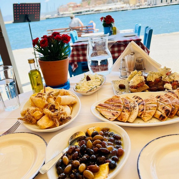 Bàn ăn taverna ven biển với nhiều đĩa meze chia sẻ kiểu Hy Lạp