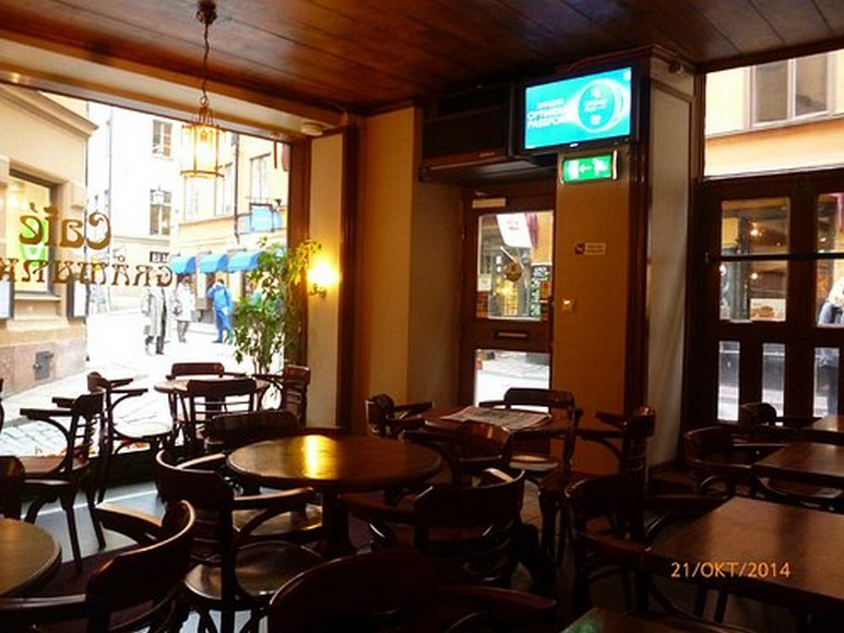 Bàn gỗ với hai tách cà phê và bánh quế cinnamon bun trong quán nhỏ phố cổ Stockholm