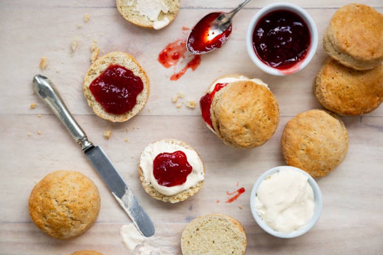 Bánh scone tách đôi phết kem clotted cream và mứt dâu