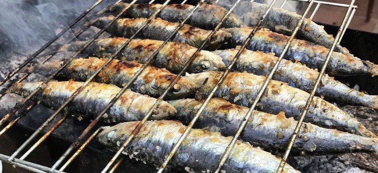 Cá mòi sardinha nướng trên bếp than ngoài trời tại một khu phố cổ Lisbon