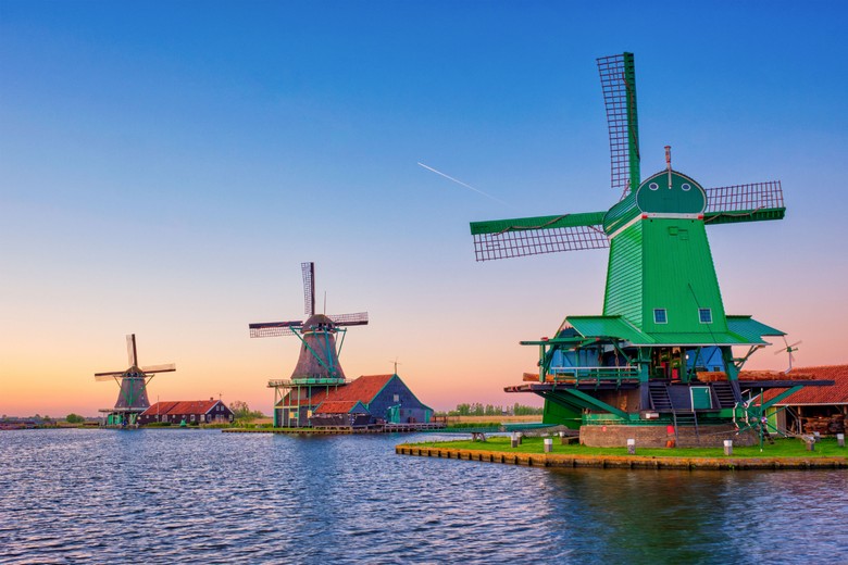 Dãy cối xay gió gỗ màu xanh bên bờ sông Zaan ở Zaanse Schans