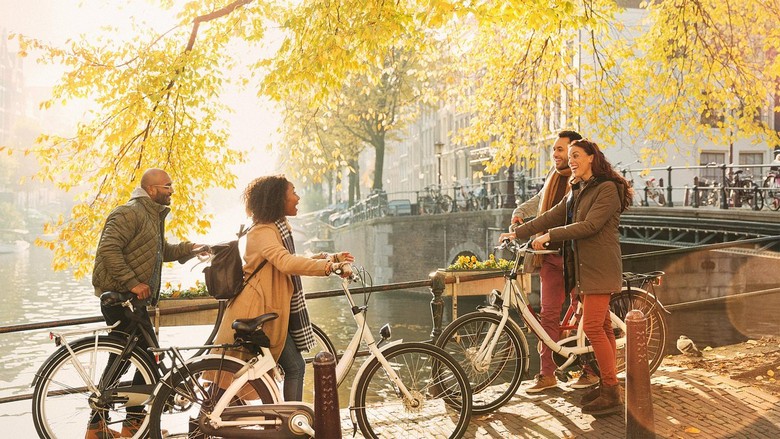 Dòng người đạp xe qua cây cầu bắc ngang kênh đào Amsterdam vào buổi sáng