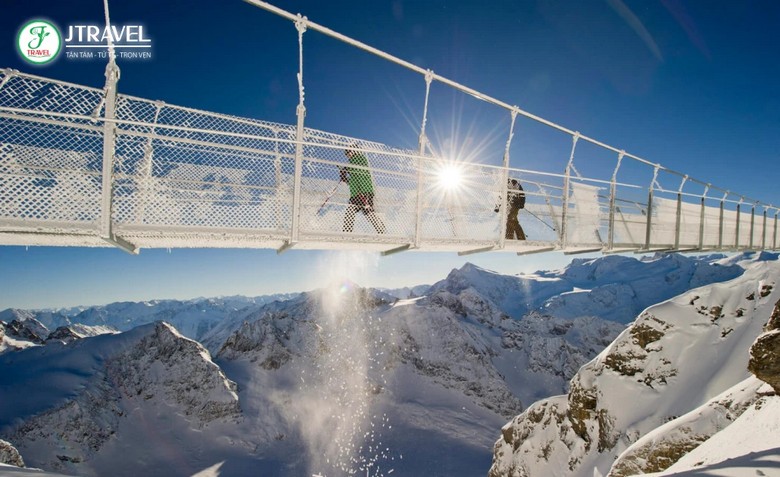 Du khách bước trên cầu treo Titlis Cliff Walk với sàn lưới thép nhìn xuống vực núi