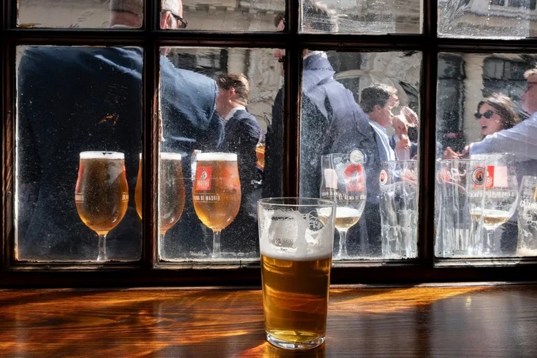 Góc phố London lúc chập tối với khách đứng trò chuyện bên ngoài pub, ly bia trên tay