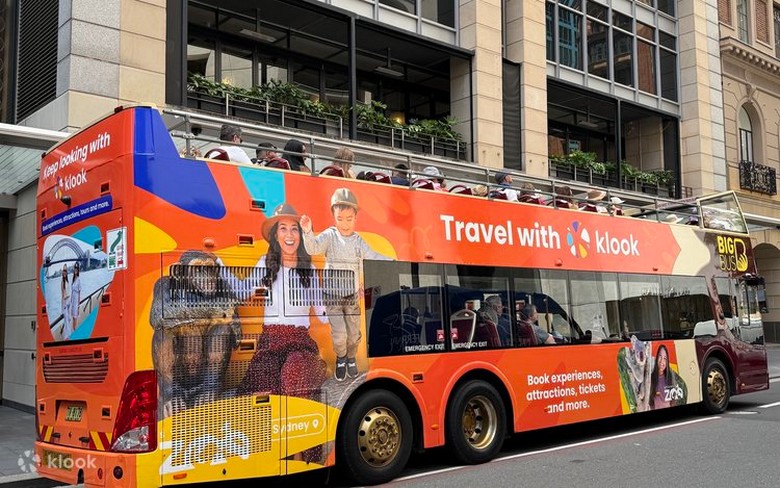 Khách ngồi tầng trên xe buýt Hop-On Hop-Off đeo tai nghe nghe thuyết minh