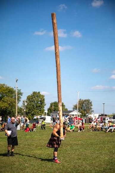 Lực sĩ mặc kilt vác thân cây lớn chuẩn bị ném trong hội thao Highland Games trên bãi cỏ