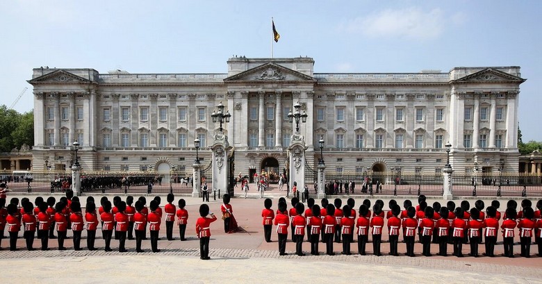 Mặt tiền cung điện Buckingham với hàng rào vàng và hai lính gác đội mũ lông gấu
