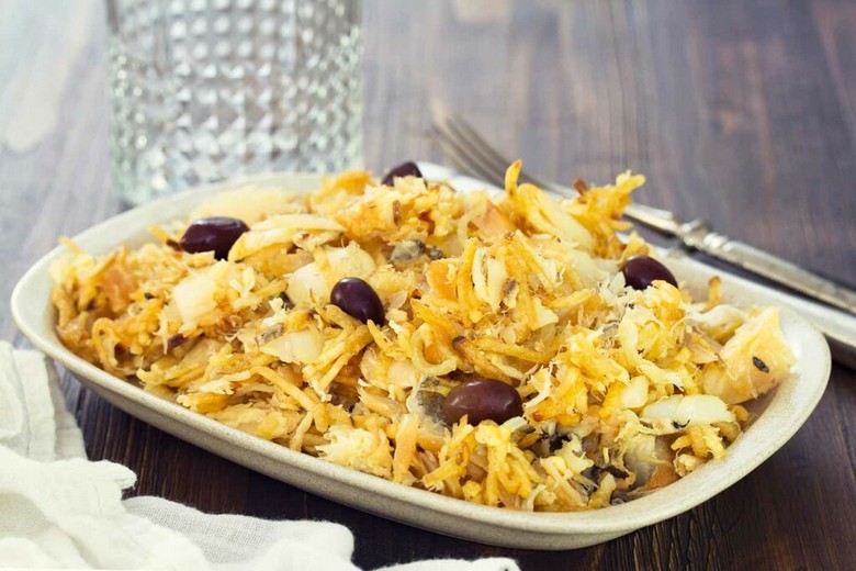 Một đĩa bacalhau nướng cùng khoai tây và ô liu đen trên bàn ăn Bồ Đào Nha