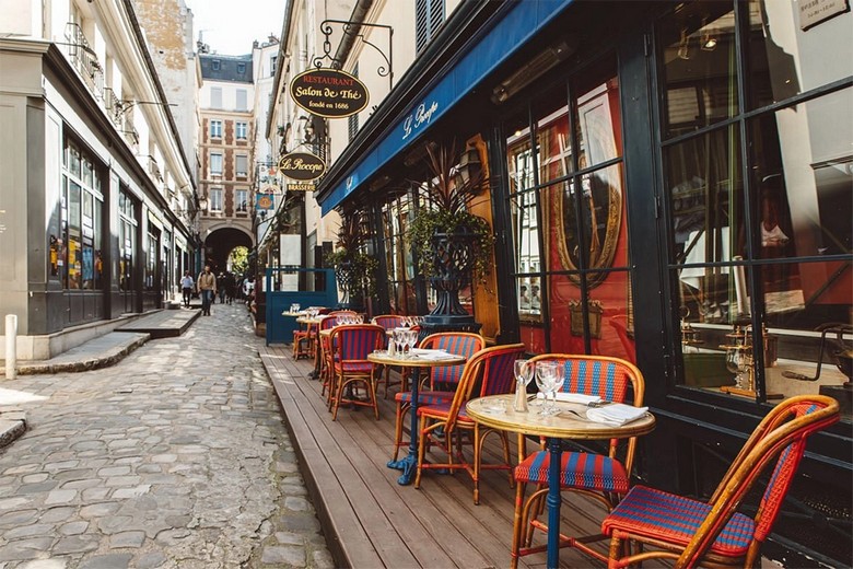 Một quán cà phê vỉa hè điển hình ở Paris với bàn ghế mây quay ra đường