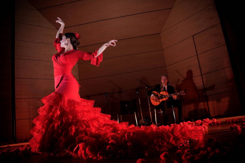 Một vũ công flamenco trong váy đỏ xoay người trên sân khấu tablao nhỏ ở Andalusia