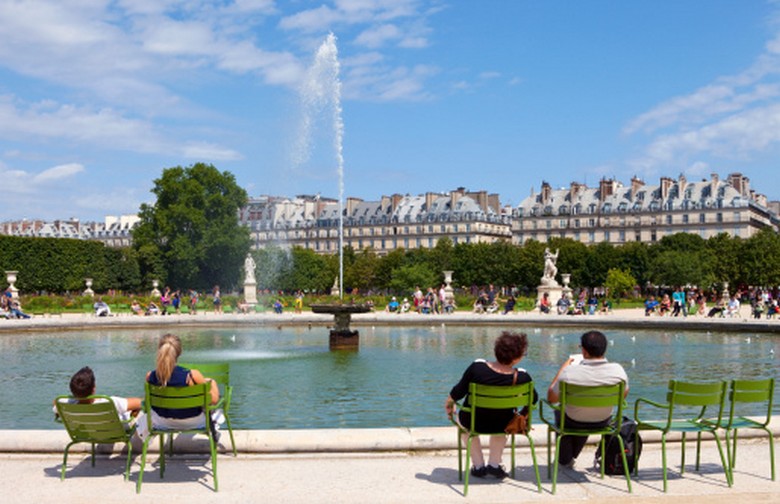 Người dân Paris ngồi tách biệt trên ghế công viên, mỗi người đọc sách hoặc dùng điện thoại riêng