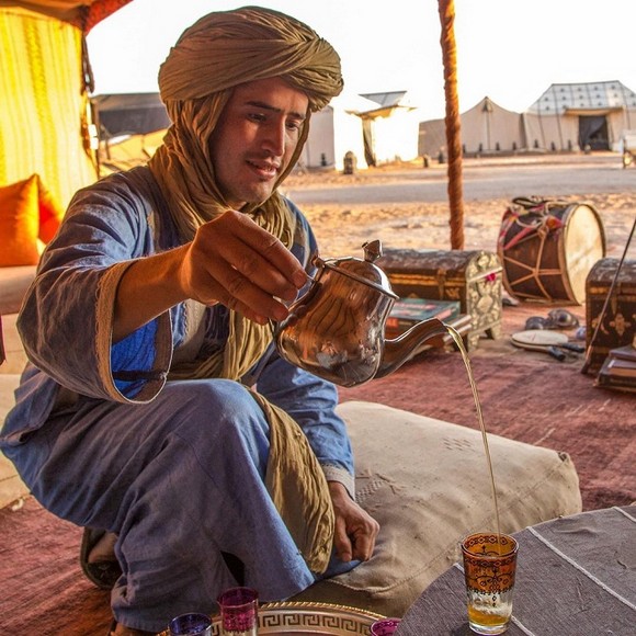 Người pha trà Maroc rót trà bạc hà từ ấm bạc cao xuống ly tạo bọt