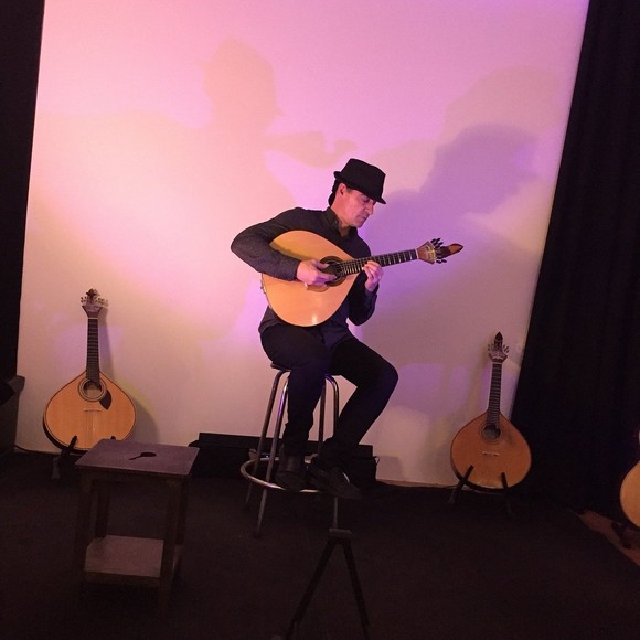 Nghệ sĩ đàn guitarra portuguesa hình quả lê biểu diễn cạnh ca sĩ trong nhà hàng ánh nến