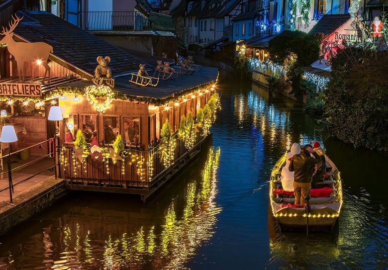 Quầy gỗ và đèn vàng tại chợ Giáng sinh Colmar buổi tối