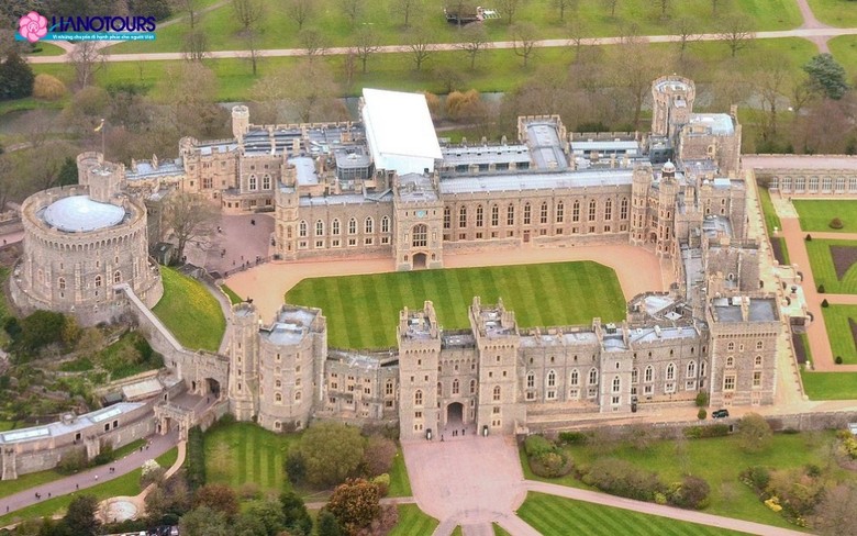 Toàn cảnh lâu đài Windsor trên đồi với tháp tròn và quốc kỳ tung bay