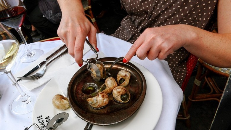 Đĩa escargot và một ly rượu vang Pháp trên bàn ăn