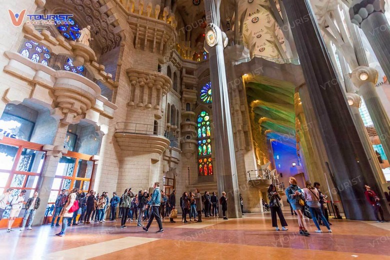 Đoàn khách tham quan bên trong Sagrada Familia dưới ánh sáng kính màu